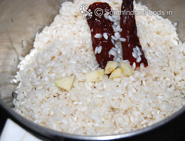 Put soaked idli rice, dry red chilli, garlic in mixie jar
