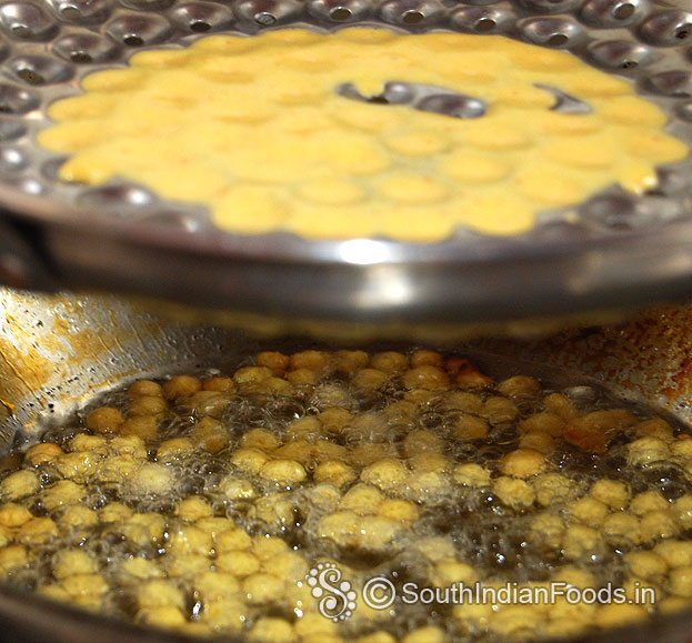 Hold boondi ladle over the pan pour batter gently shake