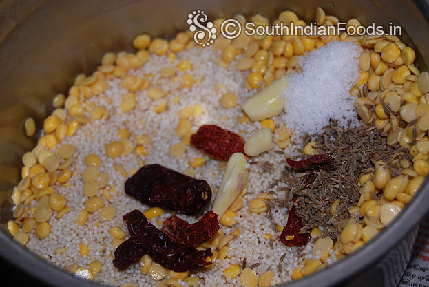 Put soaked samai rice, bengal gram, toor dal, salt, cumin, dry red chilli, garlic in a mixer jar, then coarsely grind