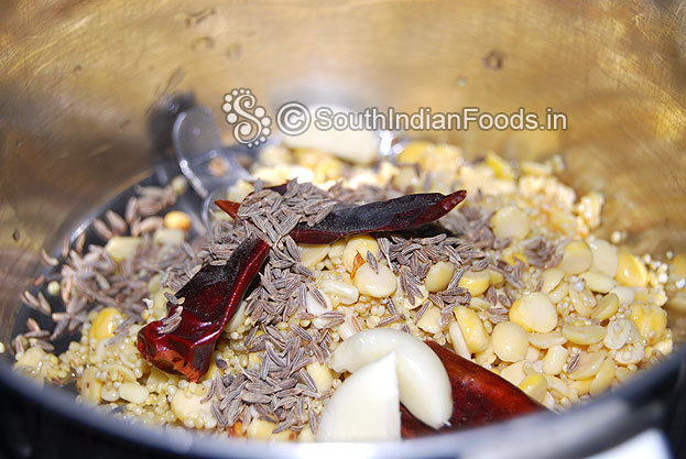 Add soaked dals, thinai arisi, dry red chilli, cumin seeds & garlic in a mixer jar & coarsely grind