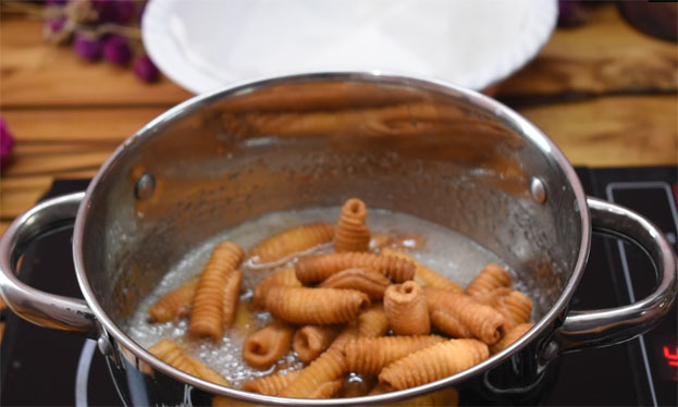 In a bowl add wheat flour, rava, ajwain, red chilli powder, turmeric powder & hot oil