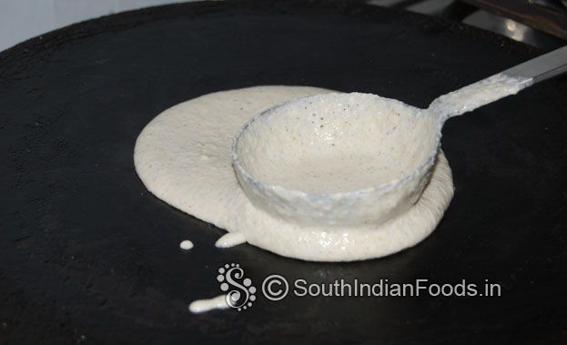 Heat iron dosa tawa, pour 1 laddle of batter, spread it[clockwise round shape]