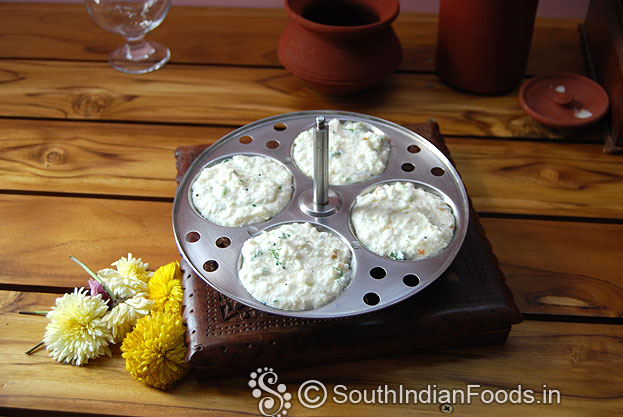 Grease idli plates with sesame oil, pour batter